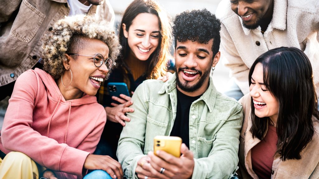 A group of multicultural millennials hanging out with one another through a company's effective audience building efforts.