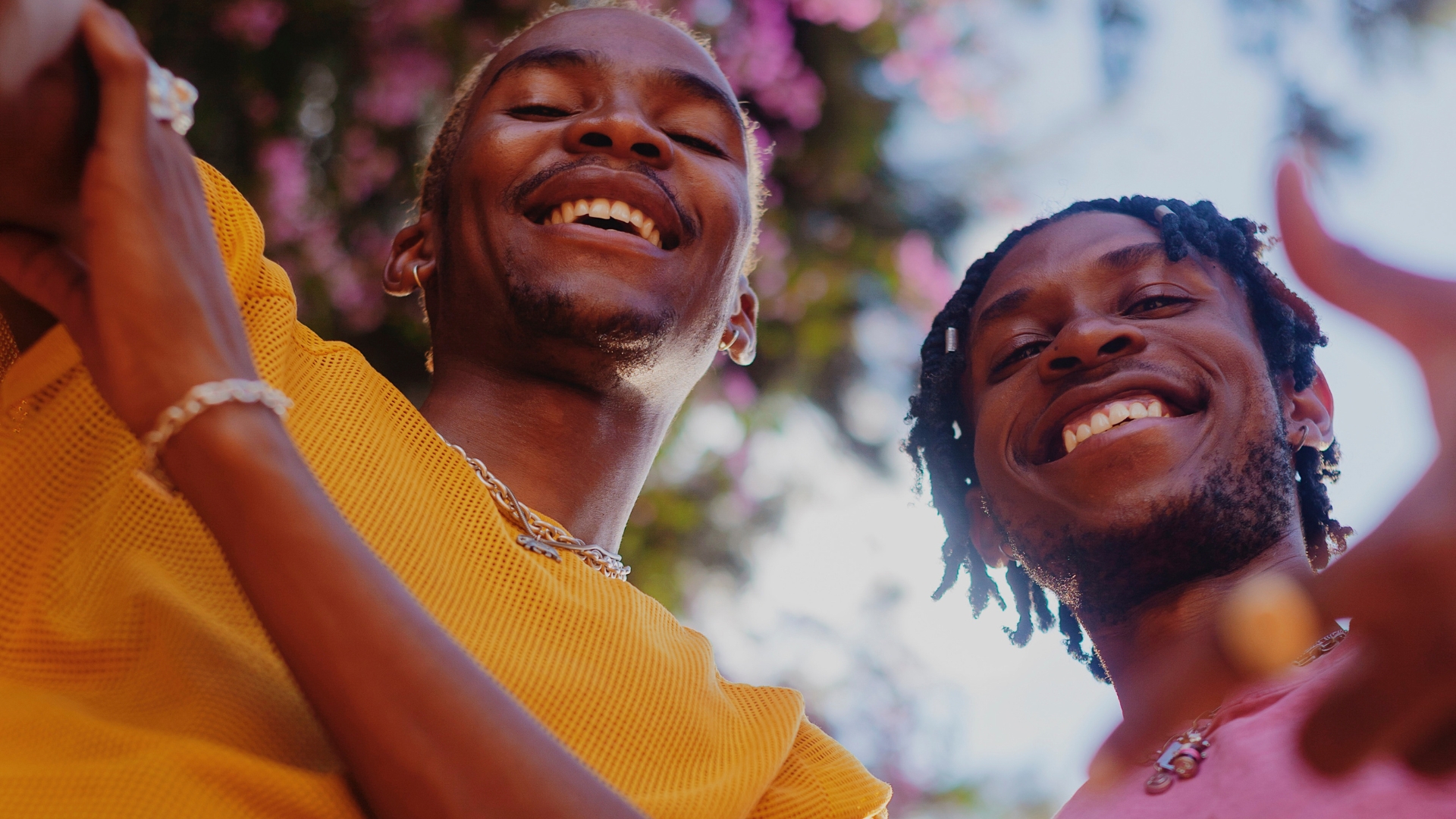 2 joyful black men in bright colored tops smiling