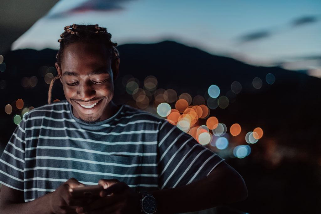 Young Black man smiling looking at smartphone