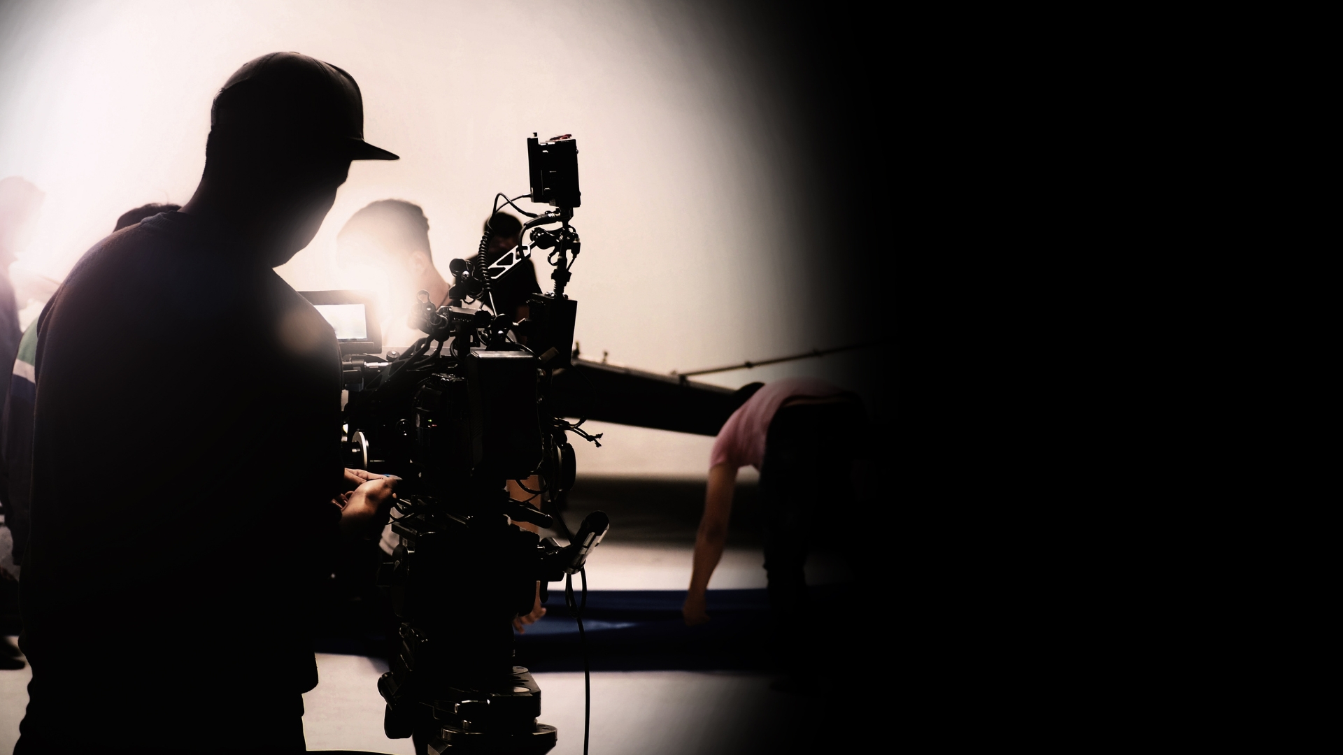 Black camera man on a set standing behind a camera on a tripod