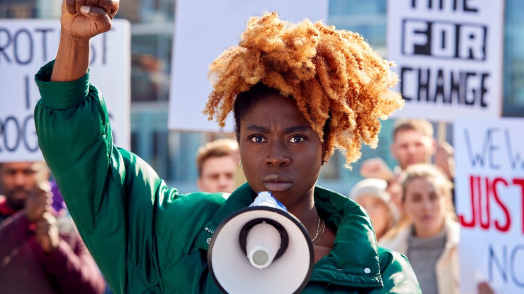 Black woman in green jacket protesting