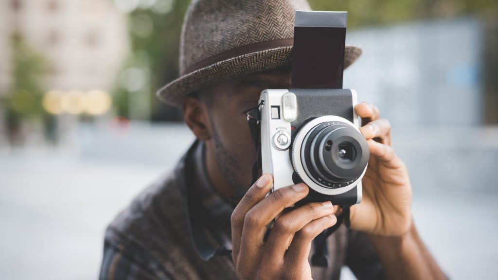 Black male content creator holding camera and shooting new footage.