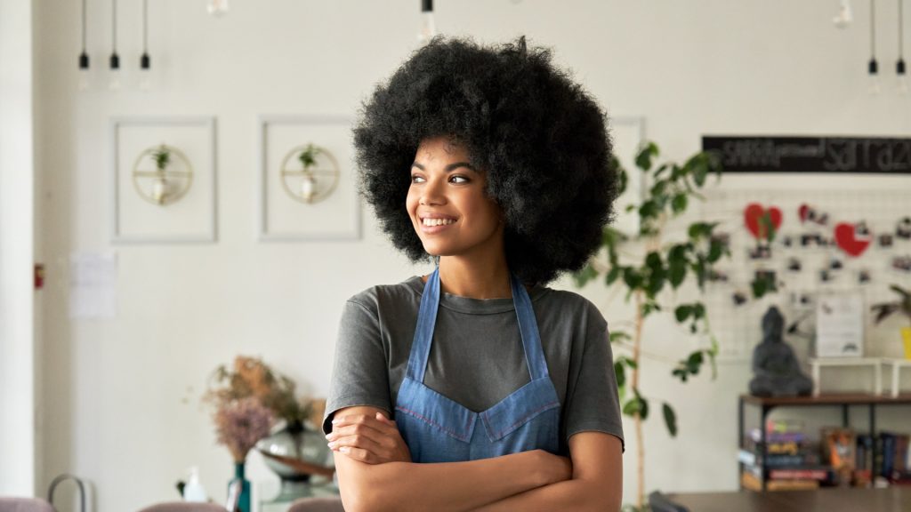 Black woman with afro standing in a flower shop and smiling