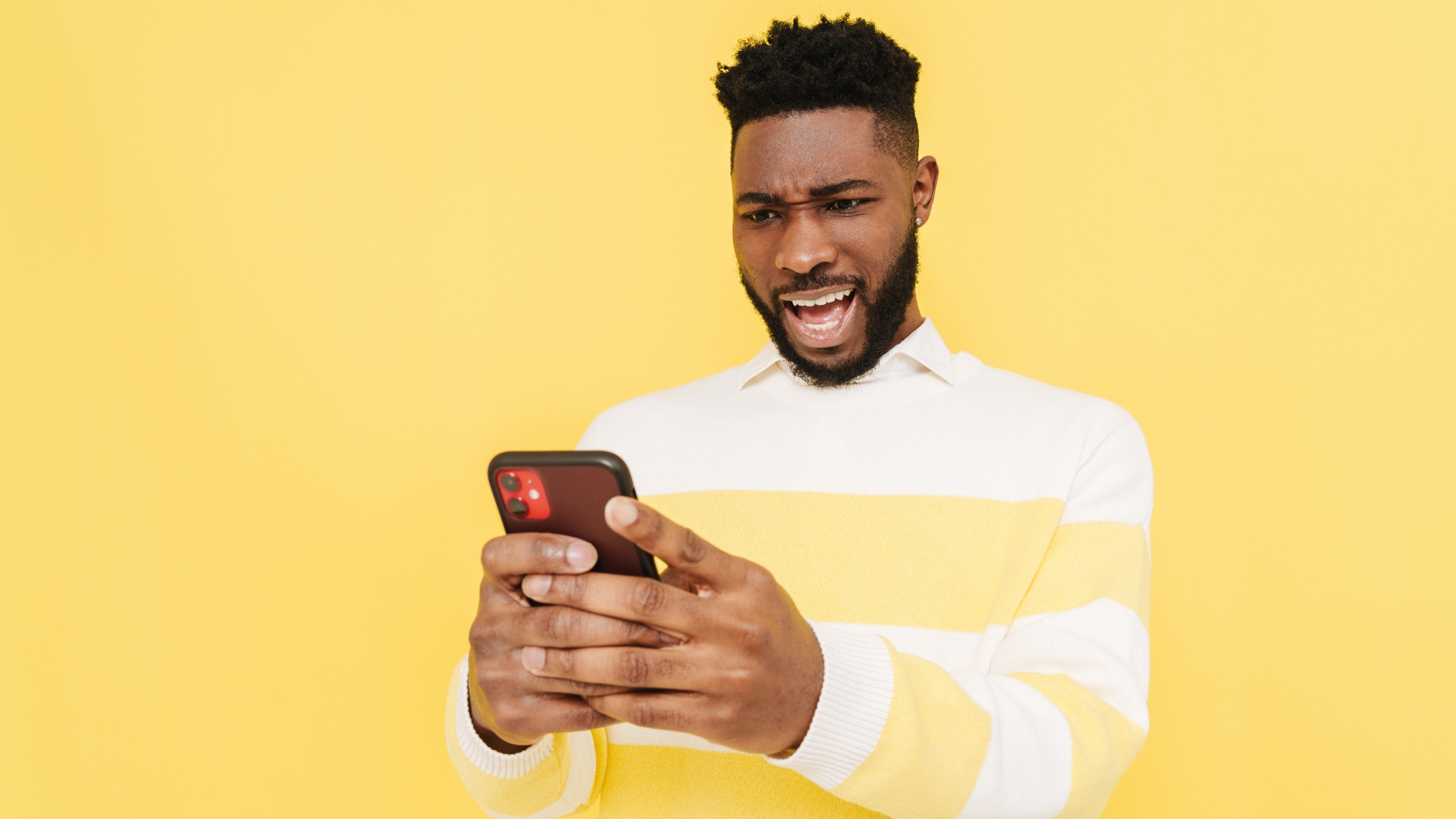 Black millennial man watching social media videos on his smart phone
