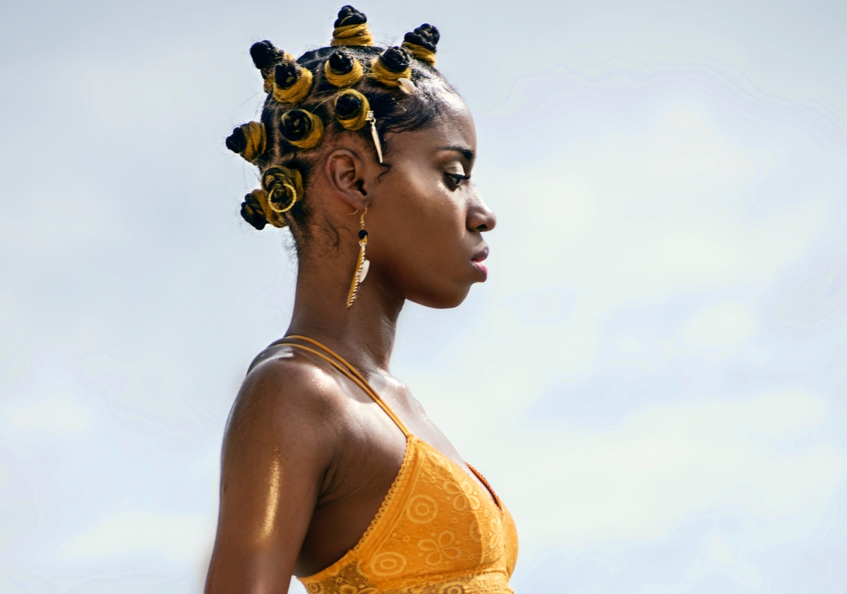 African American woman wearing bantu knots and a vibrant yellow swim bralette for Juneteenth social media engagement