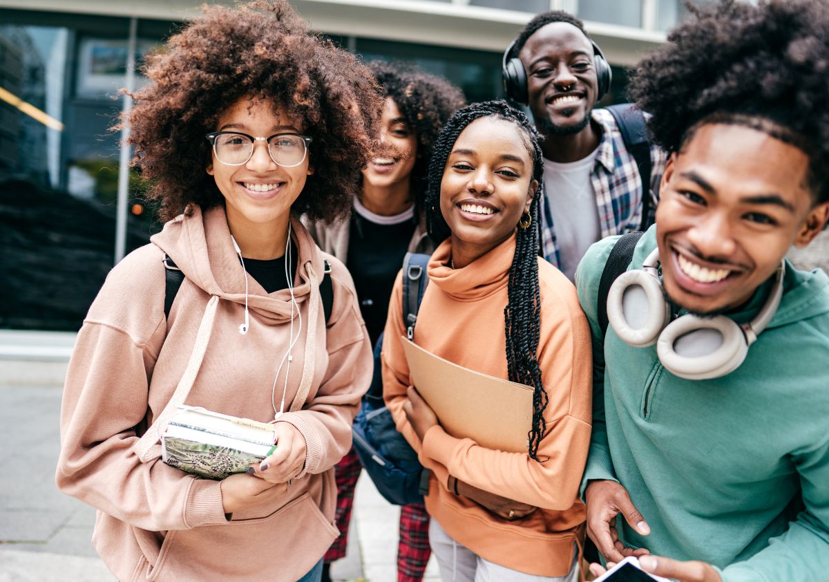 A group of young African American interns stand outside reflecting a healthy company culture