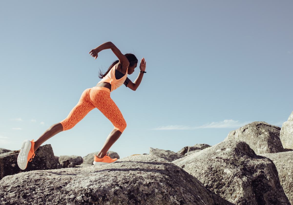 Female athlete wearing an orange 2-piece running set poses for an audience building campaign that amplifies women's voices