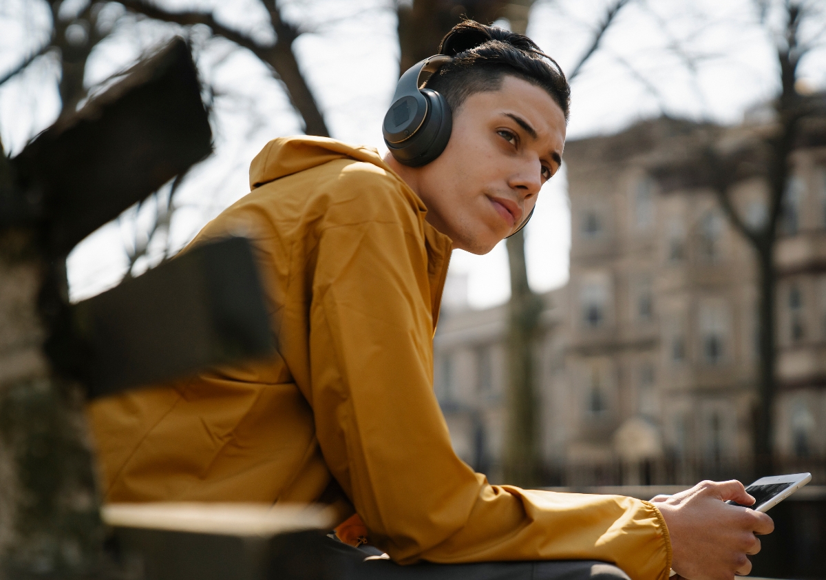 Young man of color sits on a bench in the park scrolling through his phone browsing innovative marketing ideas from brand