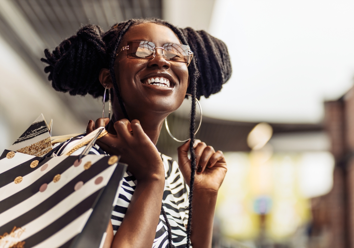 Young Black woman with braids stands holding shopping bags happy with her shopping purchases from a store with an effective ecommerce strategy