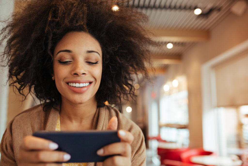 Smiling woman on her phone, checking out sales online.